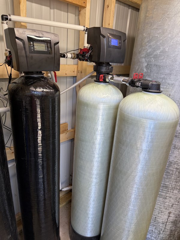 BIF iron and sulfur removal sediment filter installation with a black media tank and two fiberglass tanks