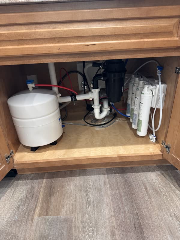 Under-sink reverse osmosis system with storage tank and filter bank installed in a kitchen cabinet