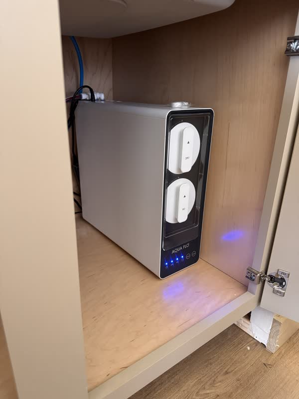 Compact tankless reverse osmosis unit with quick-change cartridges installed in a cabinet